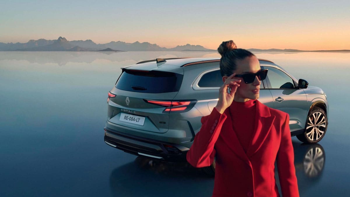 אישה מביטה אל האופק ומאחוריה רכב רנו Espace